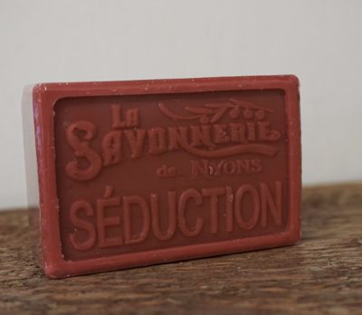 100 gram Rektangulärformad tvål från Frankrike. Tryckt text på framsidan. Mörk röd och rosa färg, doft av Seduction.